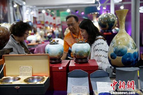 资料图：在哈尔滨举行的第六届中国-俄罗斯博览会上，参观者挑选台湾陶瓷工艺品。中新社记者吕品摄
