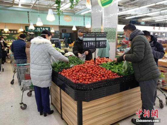 资料图：1月26日，农历大年初二，武汉超市内各种新鲜蔬菜供应充足，市民戴口罩选购。中新社记者丁喆摄