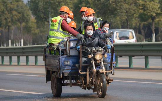 火神山医院工地的工人们正搭乘着庞益兵驾驶的电动三轮车。摄影/新京报记者许星星