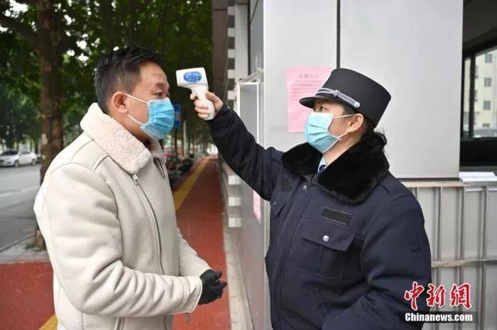 一名戴口罩的市民正在接受体温检测。中新社记者俞靖摄