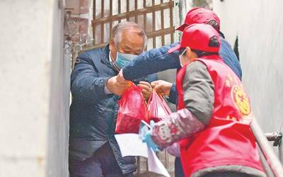 2月7日，武汉市江岸区永清街道沈阳社区工作人员为独居老人送去体温计和蔬菜，在疫情期间关心老年人生活。新华社记者李贺摄