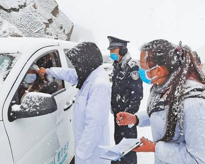 2月3日，云南省会泽县迎来降雪，执勤民警与医护人员在寒冷天气里为驾乘人员测体温，手冻得通红。叶传增付兆林摄影报道