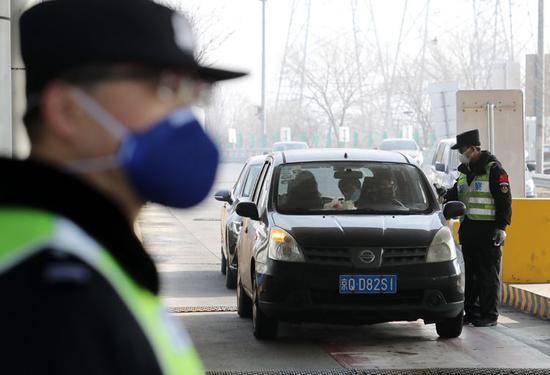 通燕高速白庙进京检查站，民警对进京车辆内的人员核查身份证并测量体温。