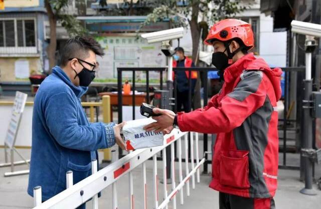 2月3日，西安一名快递员在一小区门口将货物交给收货人。新华社记者刘潇摄