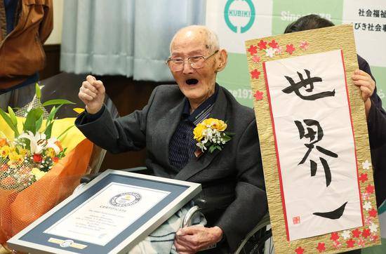  112岁的渡边和他的书法作品（朝日新闻）