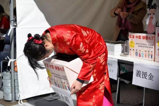  2月8日，在东京池袋，女孩身着旗袍向行人深深鞠躬，为中国抗击疫情募捐。新华社发