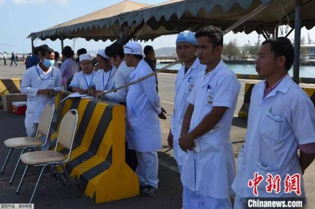 当地时间2月13日，柬埔寨防疫人员在港口等候“威士特丹”号邮轮进港。