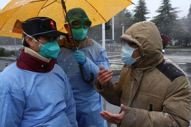 2月15日，武汉东西湖方舱医院，武汉大学中南医院副院长、东西湖方舱医院副院长李志强（左一）在雪中等待为治愈患者发放出院证明。中青报·中青网记者赵迪／摄