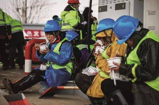 2020年1月24日，农历除夕，在武汉火神山医院施工现场吃年饭的工人。摄影/陈卓