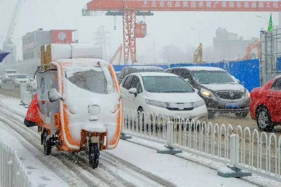  2020年2月14日，北京迎来降雪天气，快递小哥忙着送货。图|视觉中国