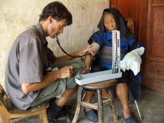 2004年，夏爱克在云南省大理州鹤庆县给当地乡亲看病。（图片由采访对象提供）