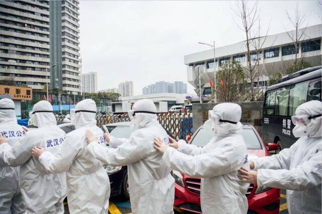 2月11日，一队准备进入武昌方舱医院执勤的民警在防护服外粘贴警察标志。摄影/湖北日报魏铼