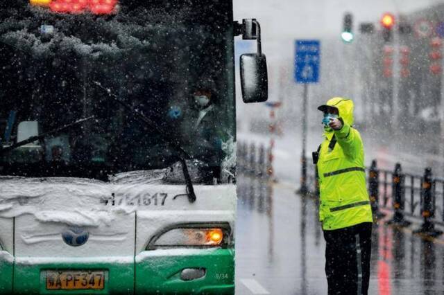 2月15日，武汉协和肿瘤医院改为定点医院收治病患，风雪中，医护、交警、公交及相关工作人员正在转运接收新冠肺炎患者。摄影/长江日报陈卓