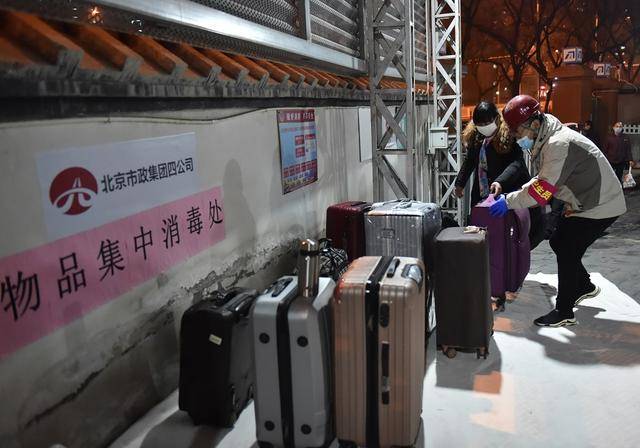 2月20日，工作人员协助返岗务工人员把行李运至物品集中消毒处。新华社发（陈钟昊摄）