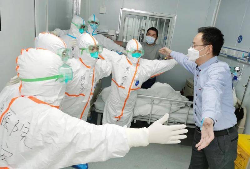  2月18日，在武汉雷神山医院，首批出院的新冠肺炎患者王先生在出院前与医护人员隔空“拥抱”以免接触传染。新华社发（高翔摄）