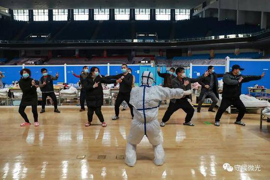  2月21日，武汉市洪山体育馆方舱医院A区内，青海省海东市互助县中医院高晓燕护士（前）正在带患者练习八段锦。中青报·中青网见习记者鲁冲/摄