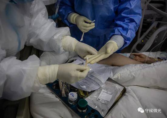 2月21日，武汉火神山医院感染八科，在为一名患者采动脉血样前，护士长为护士的手指抹上酒精，这既是为了消毒，也为了强化护士的触觉。中青报·中青网记者李峥苨/摄