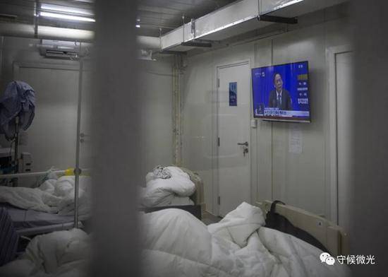 2月21日，武汉火神山医院感染八科，新冠肺炎患者在病房内的电视上收看当天在北京举办的国务院联防联控机制新闻发布会直播。中青报·中青网记者李峥苨/摄