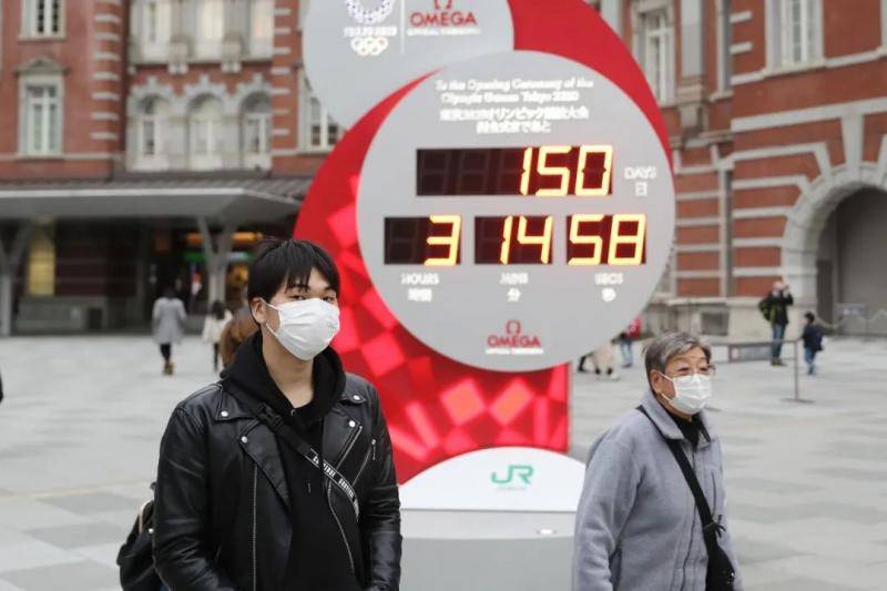  2月25日，在日本东京，行人戴口罩经过显示东京奥运会倒计时的电子屏。新华社记者杜潇逸摄