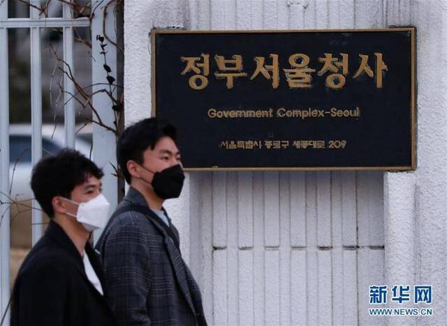  2月23日，行人从韩国首尔中央政府外墙走过。