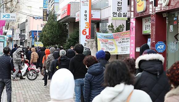  2月27日，韩国大邱市街头，民众排队购买口罩。图片来源：Yonhap