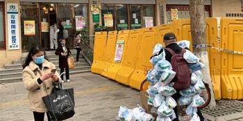 2月24日，在武汉市江岸区黄石路汉口大药房，为病人送药的小区工作者（右1）把为居民购买近100份的药挂满身上准备离开。（图片来源：新华社）