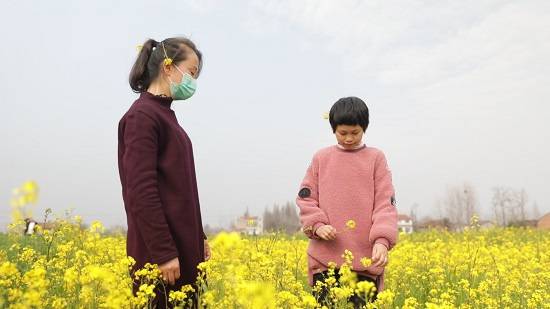 开心和妈妈在外公家的油菜花田里散步。