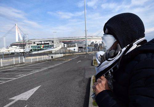  2月29日，在意大利都灵，一名男子戴着口罩站在尤文图斯安联球场外。当日意甲宣布五场比赛因疫情被推迟。新华社发（费代里科·塔尔迪托摄）