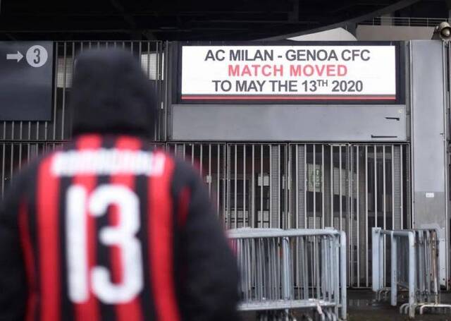 3月1日，在意大利米兰，一名AC米兰的支持者站在圣西罗球场外。标牌上显示AC米兰对热那亚的比赛推迟至5月13日进行。新华社发