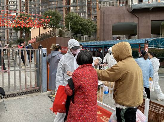 解除隔离回家的武汉市民正在小区门口接受体温检查