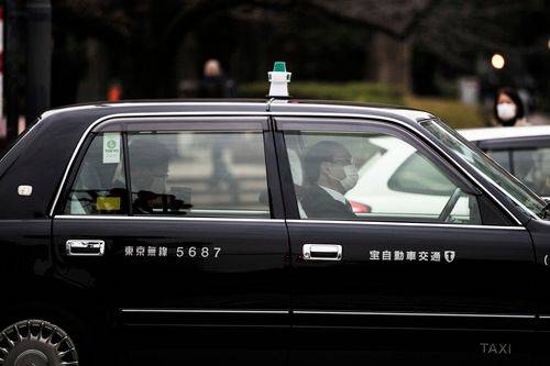 2月25日，在日本东京的一辆出租车内，乘客（左）和司机都戴着口罩。新华社记者杜潇逸摄