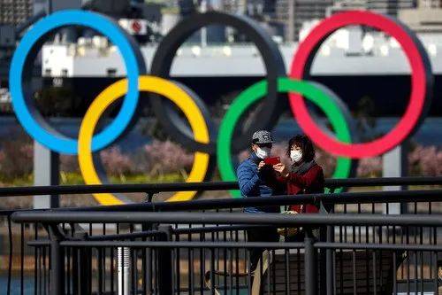 2月27日，在日本东京的御台场海滨公园，人们戴着口罩经过奥运五环。路透社发