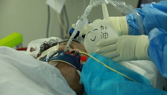 护士们为患者调整气管插管，他们用一次性手套为导管做了个支架，并写上祝福的话语。摄影：鲁巷