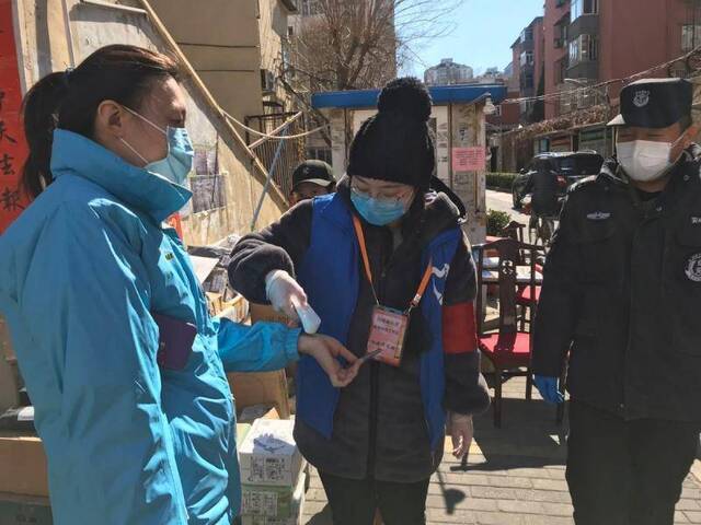 王玥在社区站岗为居民测量体温。