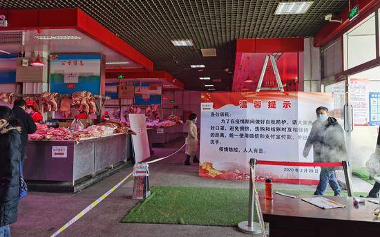 猪肉大厅进门处立着“温馨提示”牌，提醒顾客戴好口罩，保持距离，移动支付。摄影/新京报记者陈琳