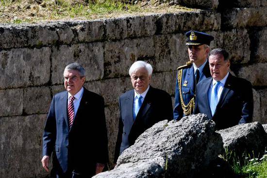 国际奥委会主席巴赫（左一）、希腊总统帕夫洛普洛斯（左二）、希腊奥委会主席卡普拉洛斯（右一）走进圣火采集仪式现场。新华社发（安东尼斯·尼科洛普洛斯摄）