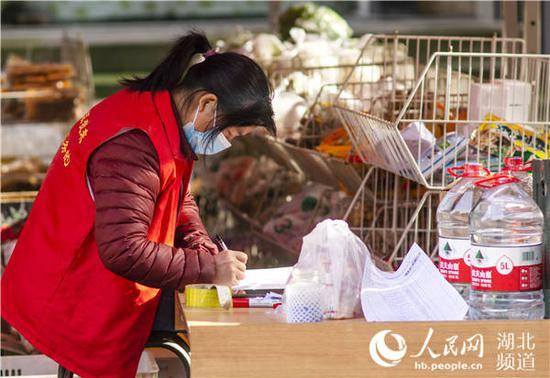 社区志愿者在分发居民网购的物资。（谭晓摄）