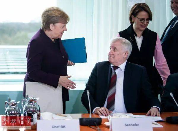 ▲资料图片：3月2日，德国内政部长霍斯特·泽霍费尔（右前）拒绝与默克尔总理握手，两人一笑置之。（德新社）