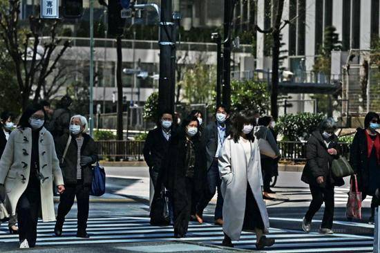 3月6日，日本东京，行人佩戴口罩在街头行走。图/法新