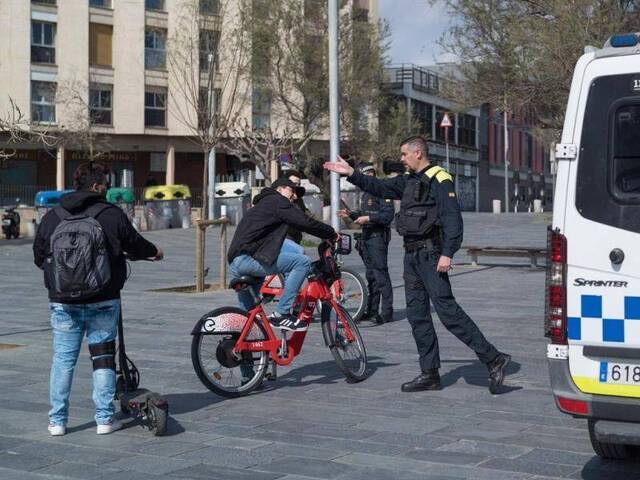 ▲当地时间3月15日，巴塞罗那街头的警察拦住行人，警告他们马上回家。图据美联社