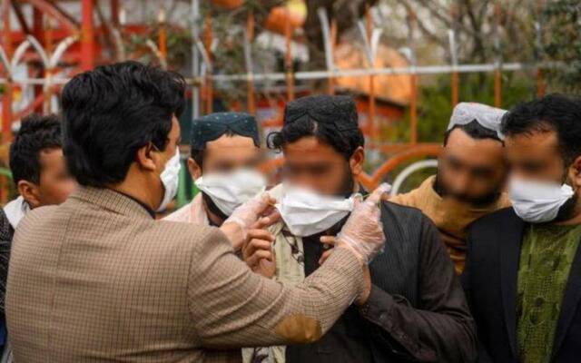 赫拉特省的一名志愿者在为民众发放口罩（法新社）
