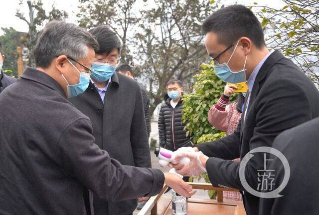 △副市长李波（左一）来到火锅店门口，按照火锅店要求依次测量体温。