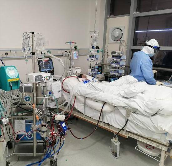武汉同济医院中法新城院区ICU内，来自西安捐赠的ECMO正在抢救一名新冠肺炎病人，医生在一旁分析病人的身体状况。冉晓供图