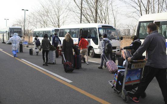 3月18日下午，新国展，海淀区转运专班带领一批回国人员上车。摄影/新京报记者浦峰