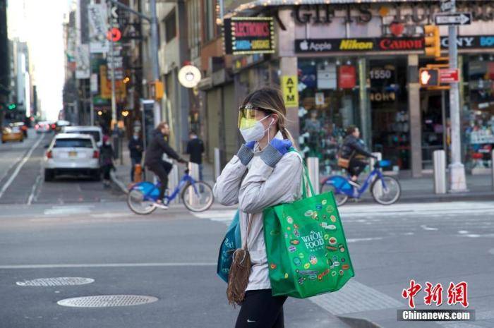 当地时间3月21日，美国纽约时代广场一位行人防护严密。中新社记者廖攀摄