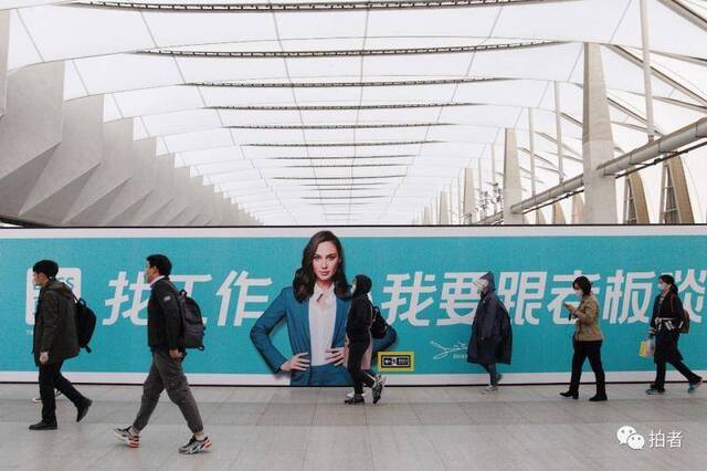 △3月24日，西二旗地铁站，乘客走过站内招聘广告牌。