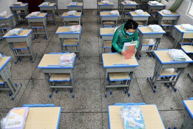  3月15日，在贵阳市云岩区第一小学初三年级集中教学点，老师为学生摆放和整理新课本。新华社图