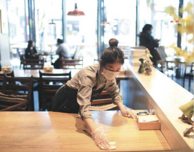 3月19日，五棵松华熙，一家餐饮店员工对用完的餐桌进行多次消毒。目前北京已出台13条具体措施，帮助个体工商户复工复产。摄影/新京报记者浦峰