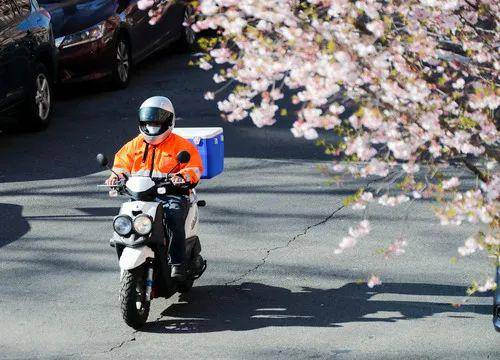 4月1日，在美国纽约，戴口罩的快递员骑车经过一处居民区。新华社记者王迎摄