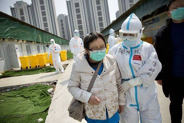 出院患者在医护人员护送下前往上车点。